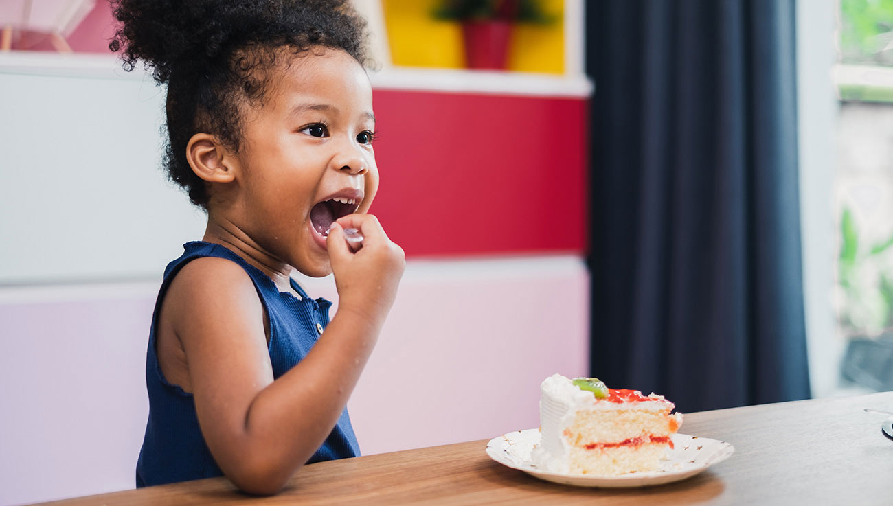 a kid eating a cake at our soft play restaurant in Glasgow